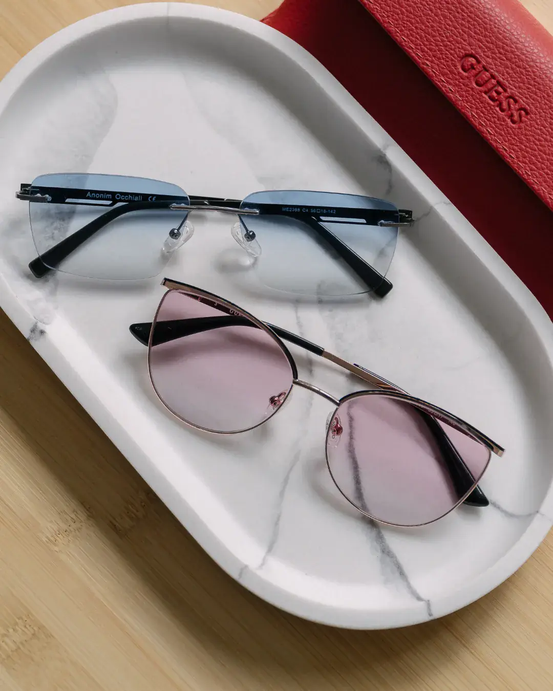 Foto comercial — ochelari de soare Guess pe tavă de marmură